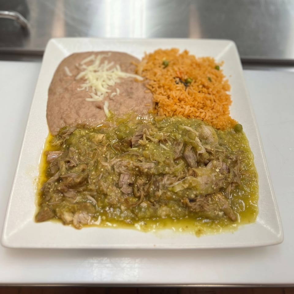 A plate of green chile pork, refried beans with cheese, and Spanish rice.