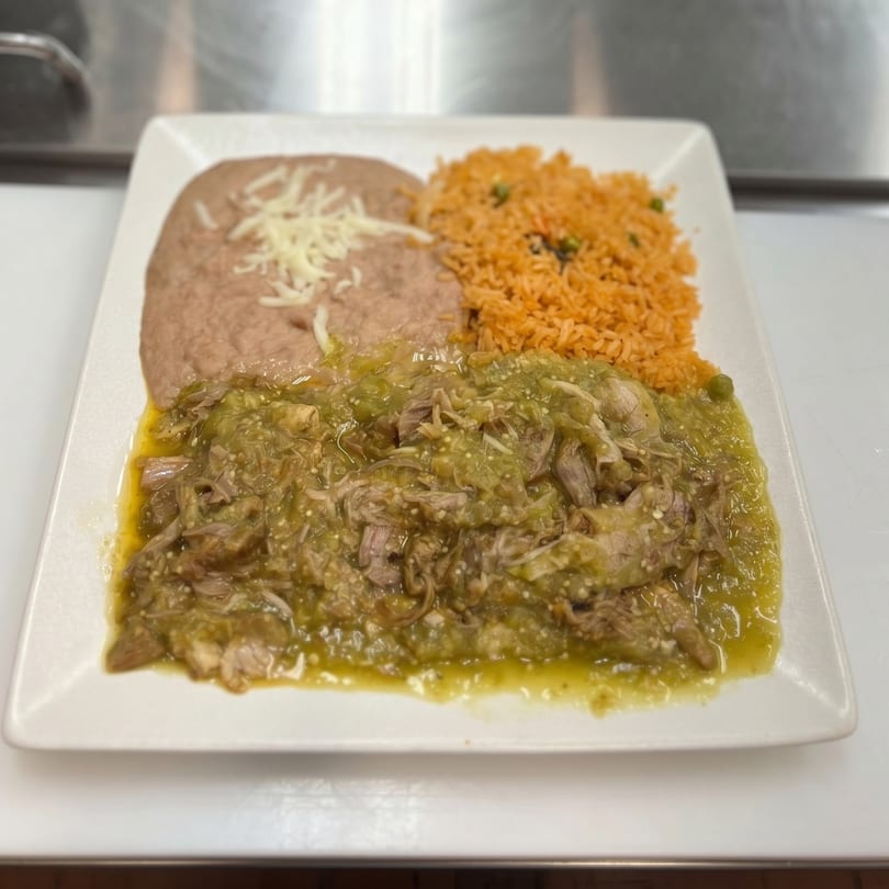A plate of green chile pork, refried beans with cheese, and Spanish rice.